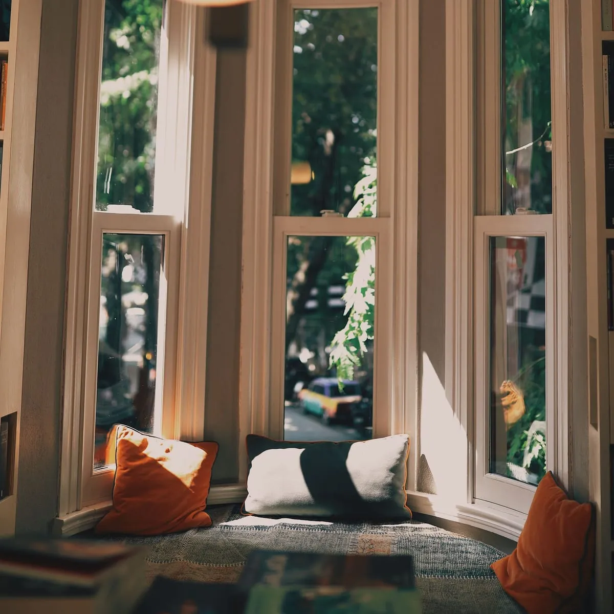 Cozy bay window reading nook with cushions in warm light