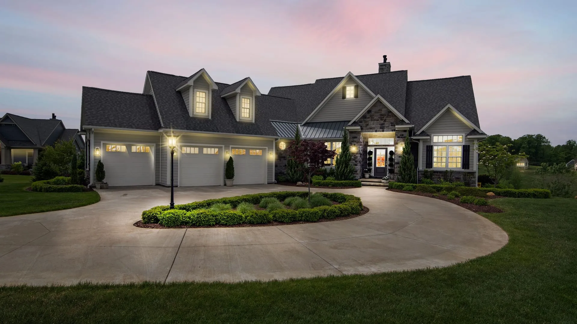 Luxury home at dusk with stone accents and large energy-efficient windows glowing warmly