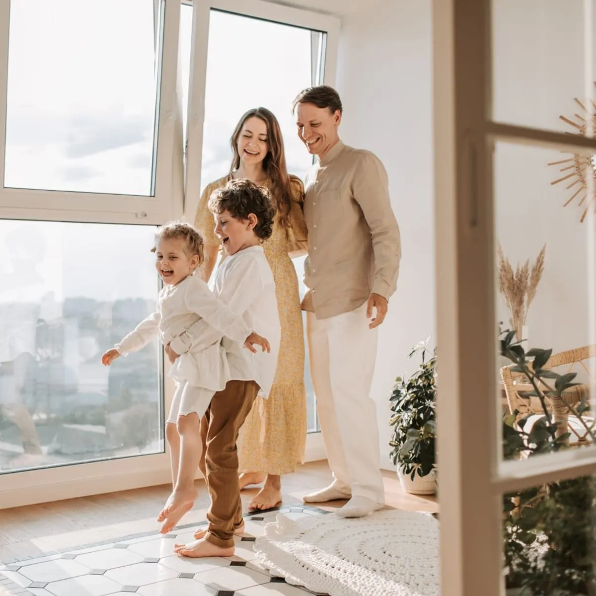 Family relaxing in a sunlit living room next to large windows